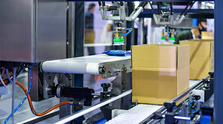Chaîne de production automatisée avec des boîtes en carton sur un convoyeur, illustrant l’importance d’éviter les erreurs les plus courantes dans l’emballage industriel pour assurer un conditionnement efficace et sécurisé.