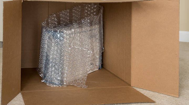 Produit emballé dans du film à bulles à l’intérieur d’une grande boîte en carton, illustrant l’importance d’éviter les erreurs les plus courantes dans l’emballage industriel pour protéger efficacement les marchandises fragiles.